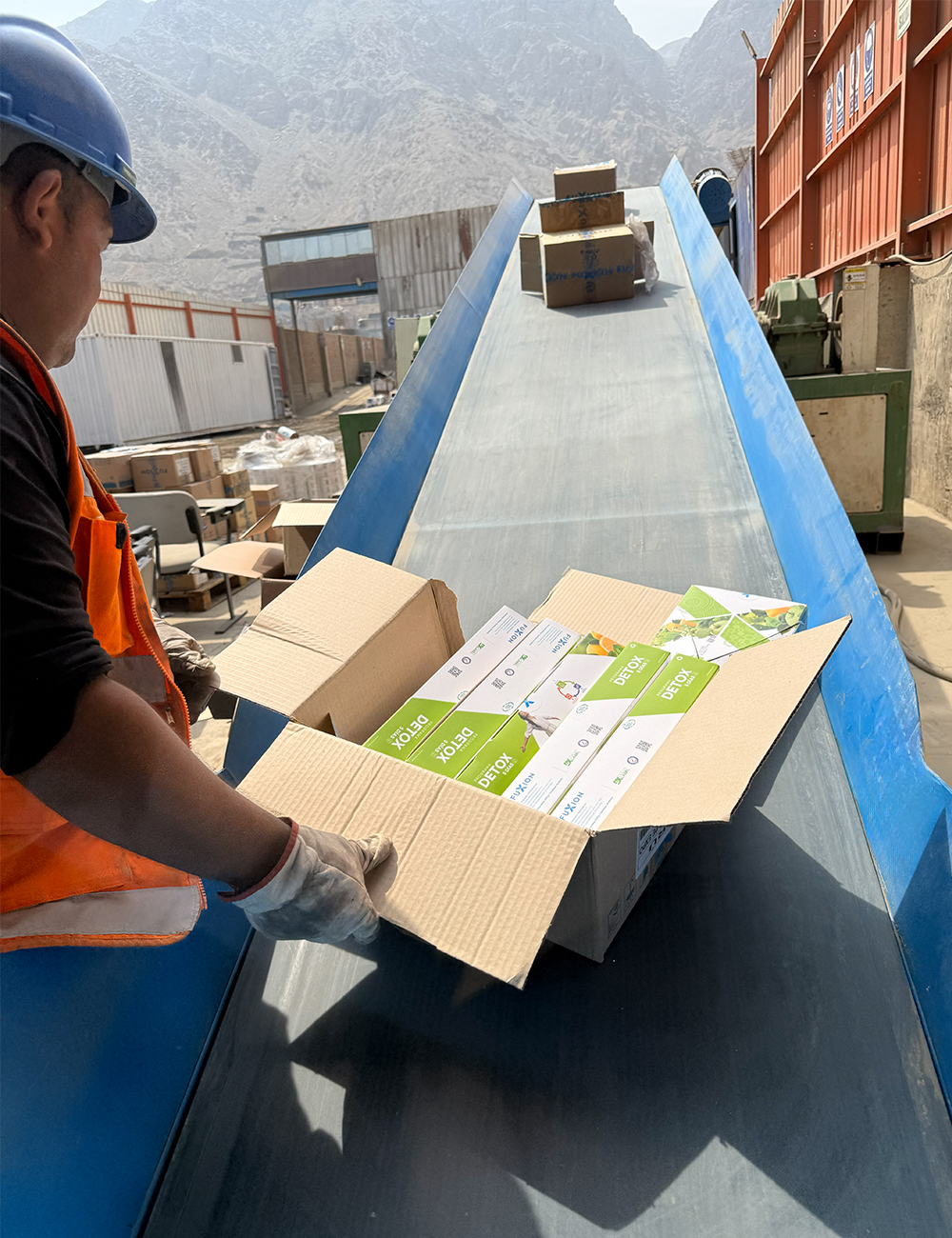 Operario de Caryma supervisando la destrucción de productos alimenticios vencidos en faja transportadora industrial.