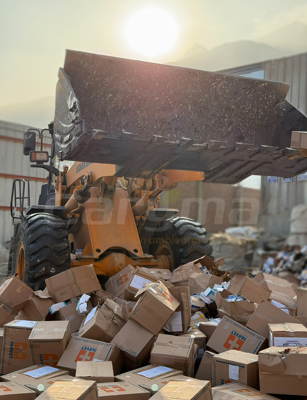 Cargador frontal realizando la destrucción de mercadería y cajas de productos en desuso para su disposición final segura.